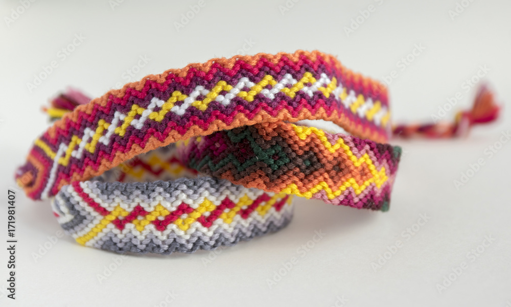 Three simple handmade homemade natural woven bracelets of friendship on white background, rainbow colors, checkered pattern Three simple handmade homemade natural woven bracelets of friendship on white background, rainbow colors, checkered pattern