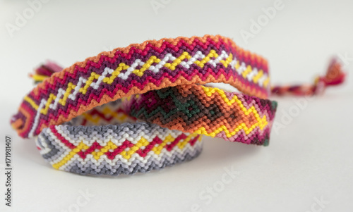 Three simple handmade homemade natural woven bracelets of friendship on white background, rainbow colors, checkered pattern