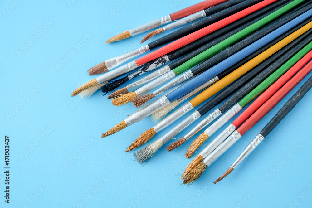 Row of artist paint brushes close up on blue  background