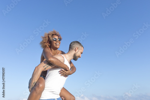  Couple piggy back on the beach in the summer