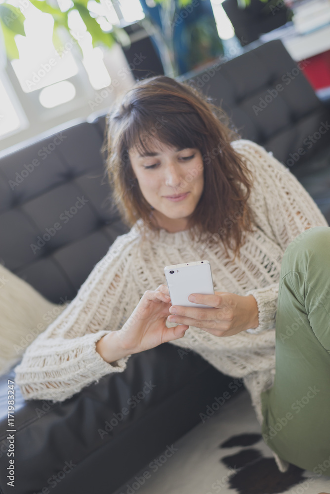 Cheerful woman speaking on mobile phone, sitting on living room Cheerful woman speaking on mobile phone, sitting on living room