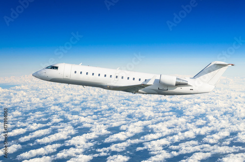 Passenger airplane flies on a flight level against a background of clouds and a blue sky