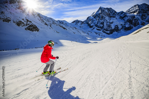 Teenager skiing in Italian Alps. In background blue sky and shiny sun and Ortler in South Tirol, Italy. Adventure winter extreme sport.