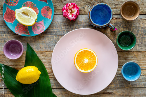 Crockery pattern. Cups and plates near tropical leaves and fruits on wooden background top view