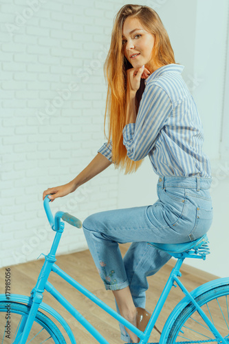 Cheerful young woman standing near bicycle