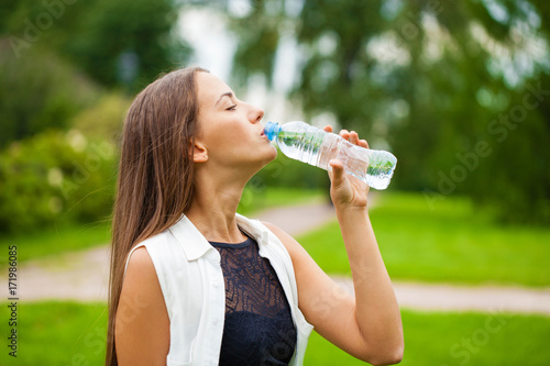 Portrait of young beautiful dark haired woman drinking water