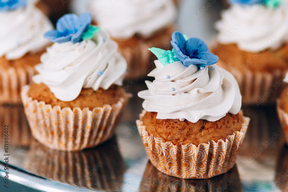 muffins with whipped cream and frosting on a silver table in stainless steel muffins with whipped cream and frosting on a silver table in stainless steel