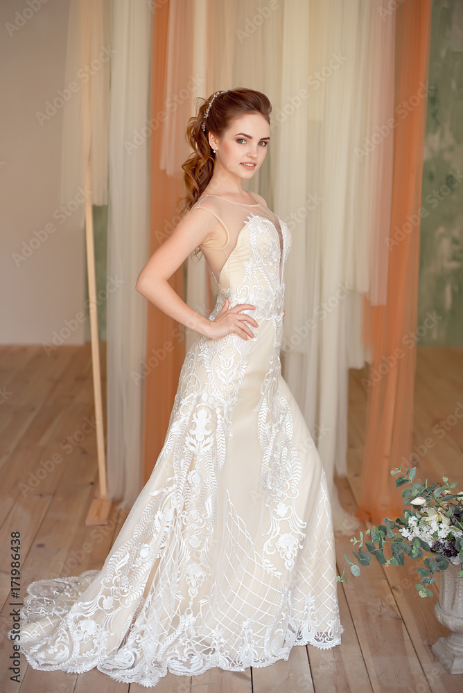 Full-length portrait of Beautiful luxurious female model with medium brown hair in a long white wedding dress in the room. Bridal clothes concept. Stylish wedding dress. Full-length portrait of Beautiful luxurious female model with medium brown hair in a long white wedding dress in the room. Bridal clothes concept. Stylish wedding dress.