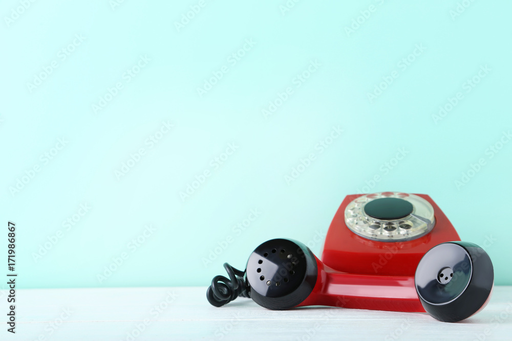 Fototapeta premium Red retro telephone on white wooden table