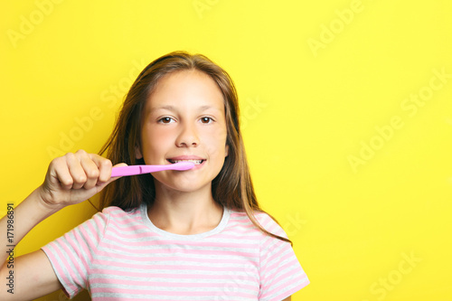 Portrait of beautiful girl with toothbrush on yellow background