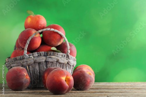 Sweet nectarines in basket on grey wooden table
