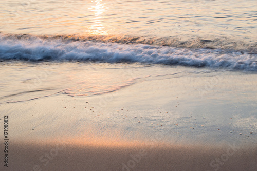 Sunset soft beautiful ocean wave on sandy beach. romantic travel background.