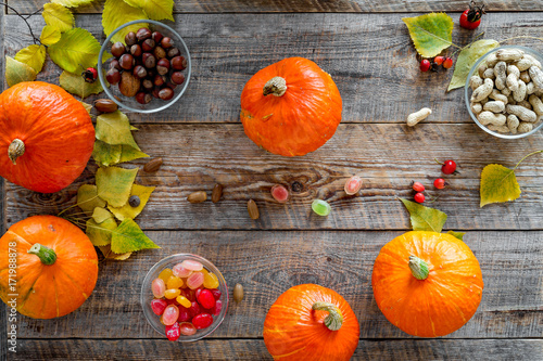 Pumpkin harvest. Pumpkins near nuts and autumn leaves on wooden background top view photo