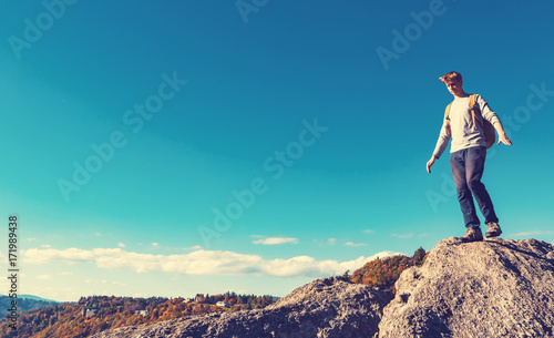 Man walking on the edge of a cliff high above the mountains 