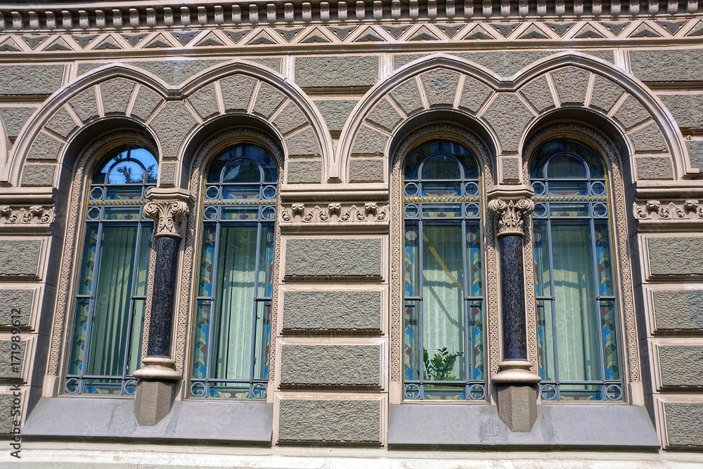 два старинных окна на серой стене каменного дома 
