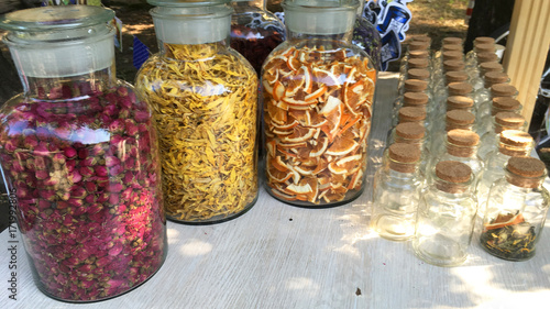 Dry petals and buds in a glass bottles for flower tea. Dry roses, sunflowers, orange for perfumes, cosmetics, alternative medicine, herbal tea and bath. Colored organic herb. 