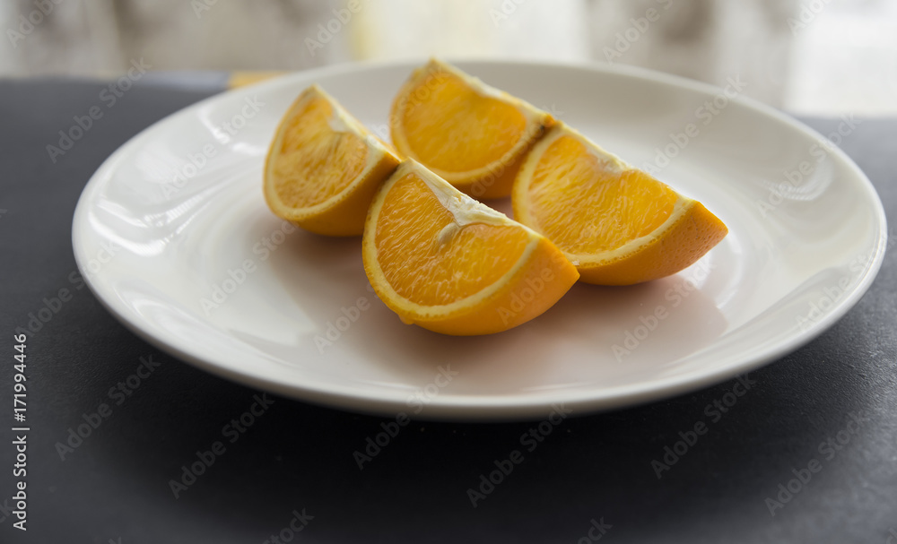 Orange cut in to slices on the white plate Orange cut in to slices on the white plate