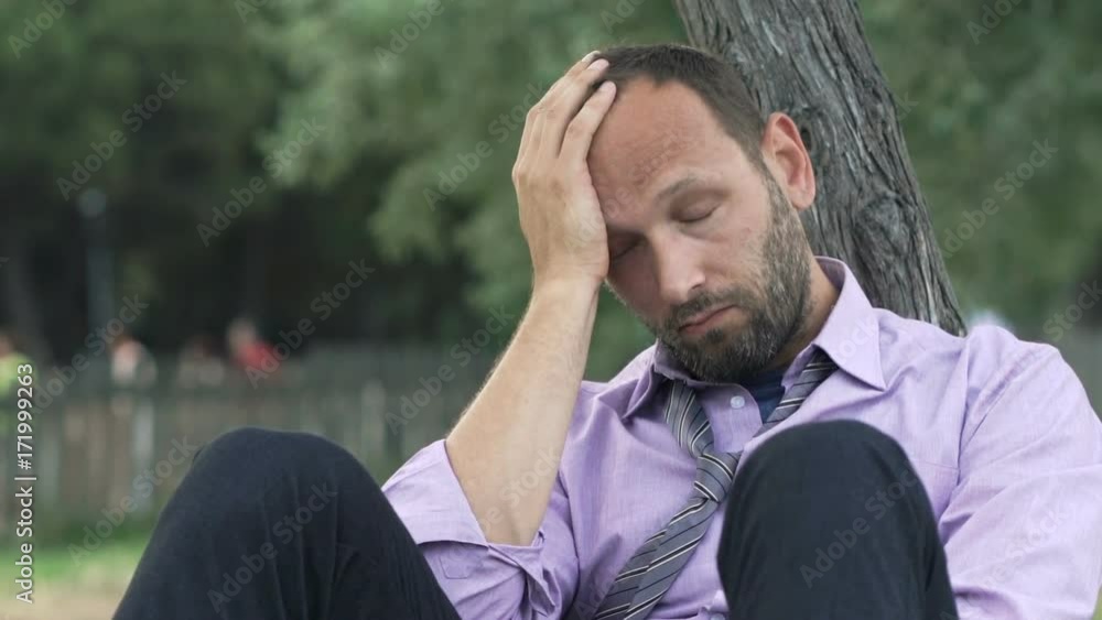 Portrait of sad, tired businessman sitting on grass in park
Portrait of sad, tired businessman sitting on grass in park