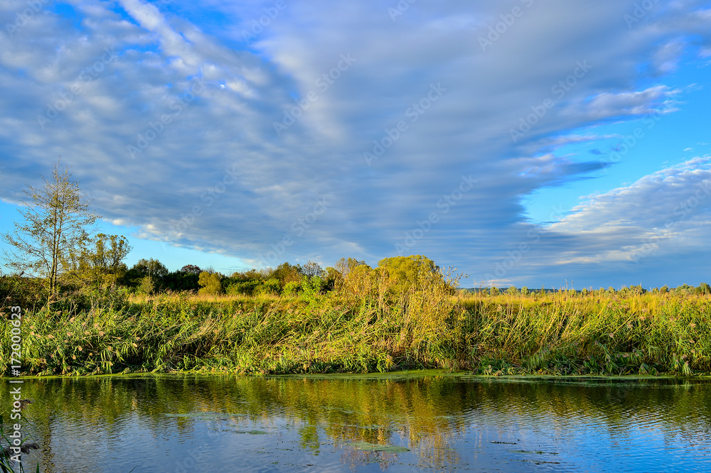 Colorful autumn landscape with a river and clouds