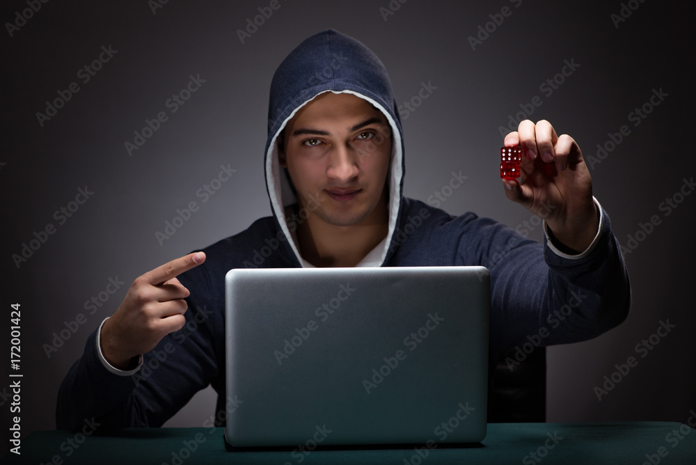 Young man wearing a hoodie sitting in front of a laptop computer Young man wearing a hoodie sitting in front of a laptop computer