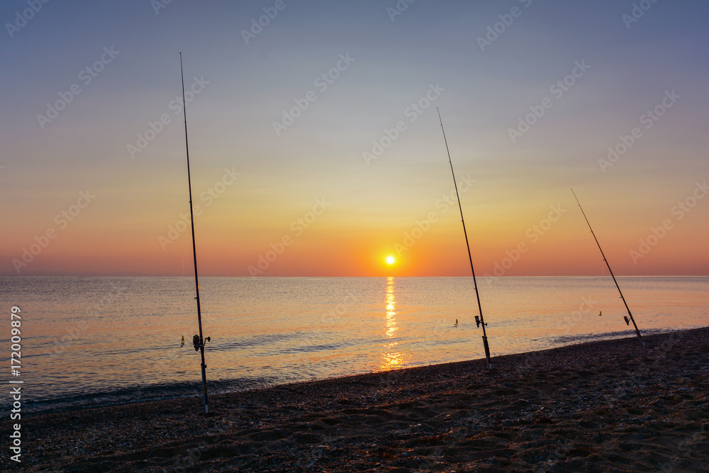 Fishing rods on the sea shore at sunrise