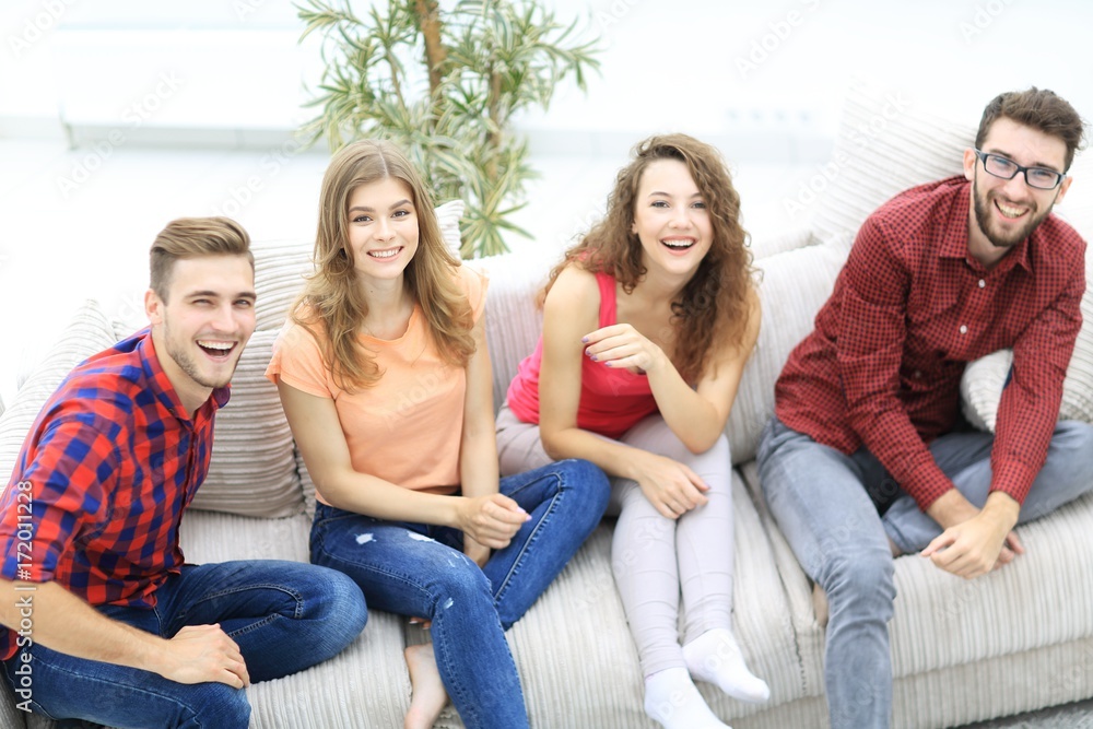 group of cheerful friends watching videos, sitting on the couch group of cheerful friends watching videos, sitting on the couch