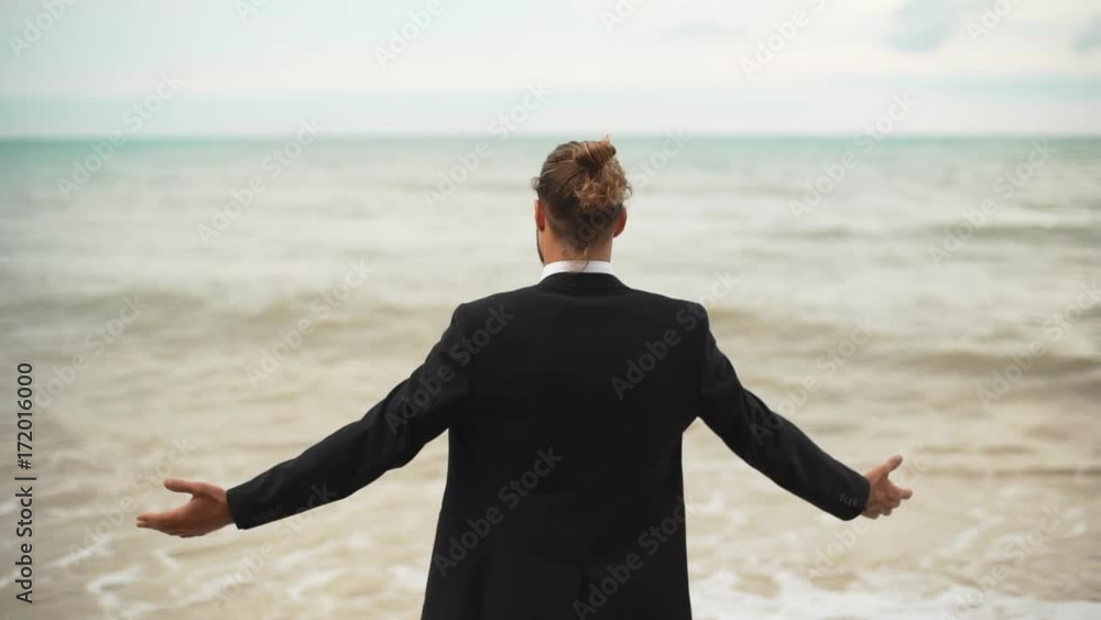 businessman with tied hair greeting sea with open arms backside to camera slowmotion businessman with tied hair greeting sea with open arms backside to camera slowmotion