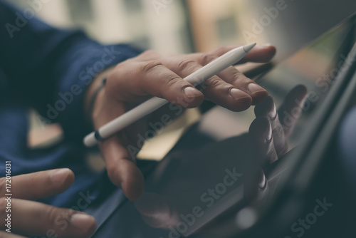 Businessman holding tablet on hand and working at office.Touching fingers tablet screen.Blurred background.Horizontal.