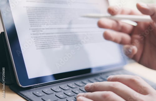 Blogger working mobile touchpad for work.Closeup view of male hands typing electronic tablet keyboard-dock station and using stylus pen.Horizontal.Blurred background. photo