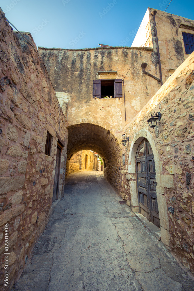 Old narrow street with stone arch at Atsipopoulo, Rethimno, Crete, Greece.