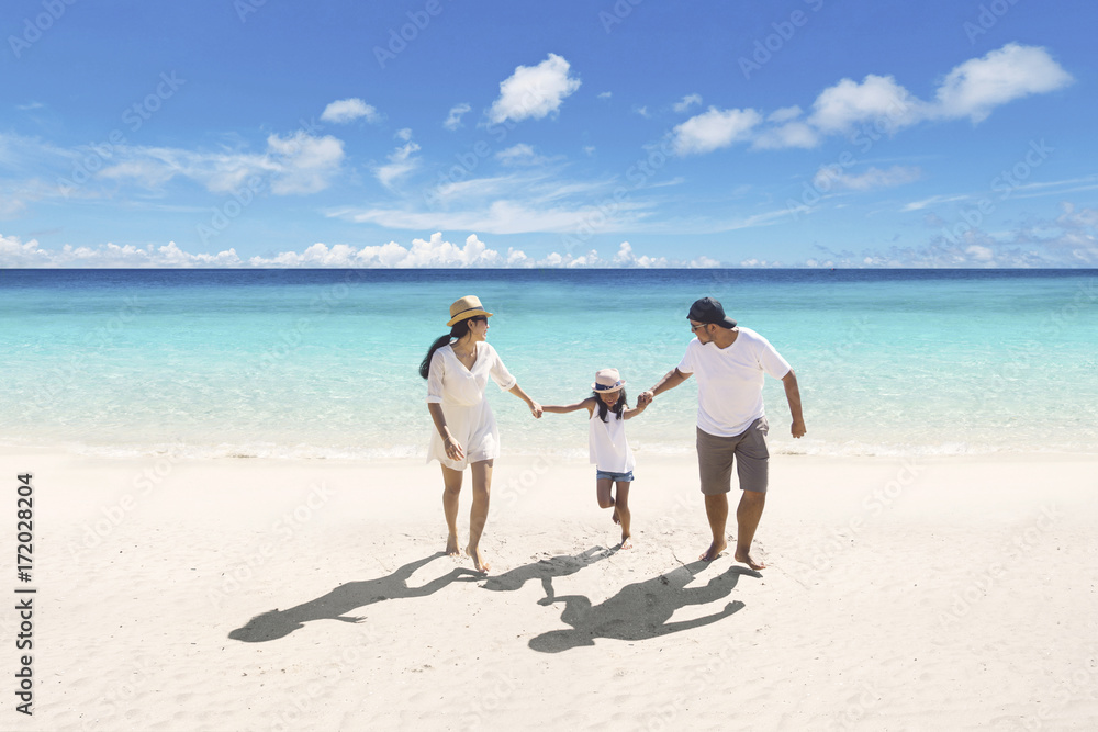 Asian family walking together on the beach