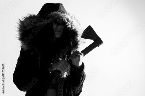 Foto Spooky woman in a coat with fur hood, standing holding an axe
