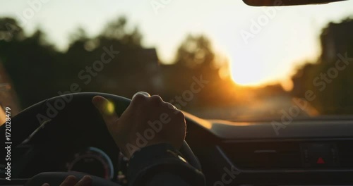 Man Driving a Car at Sunset. SLOW MOTION 4K DCi. Male Hand on steering wheel close up. Beautiful Road in blurred background.
