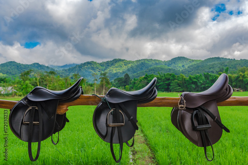 saddle in horse farm with mountain and sky background