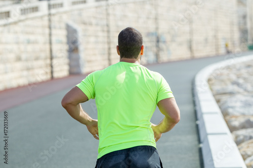 Closeup Back View of Strong Man Running on Road