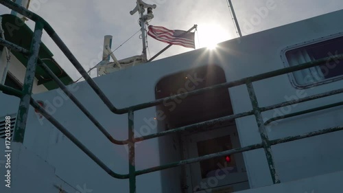 Slowmotion clip of ferry control tower and united states flag waving in the wind with sun background photo