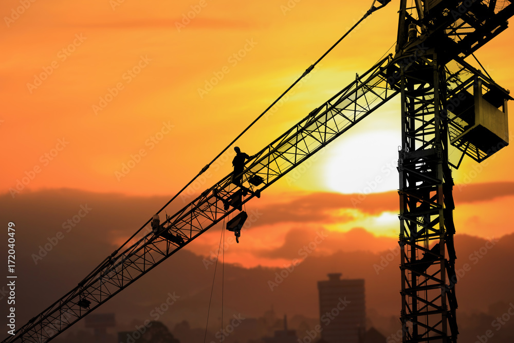Silhouette Tower crane construction with worker in sunset and copy space add text
