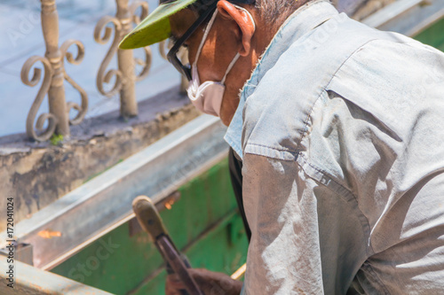 elderly welder works steel welding repair on roof high. select focus with shallow depth of field