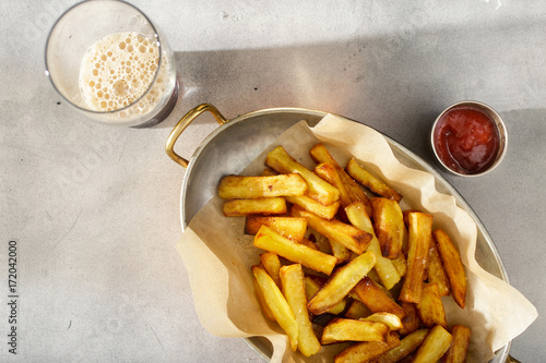 Pan of homemade french fries with ketchup and dark beer