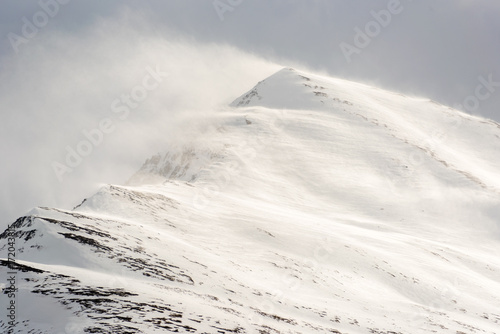 Wind blows snow away from mountain peak.