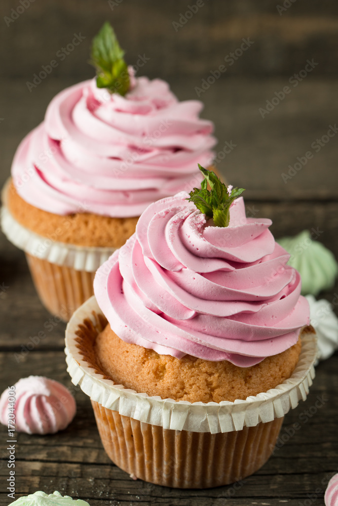 Closeup of cupcakes with vanilla, berries, pink and white cream, chocolate and sprinkles on wooden background. Selective focus. Sweet dessert tasty food concept muffin. Closeup of cupcakes with vanilla, berries, pink and white cream, chocolate and sprinkles on wooden background. Selective focus. Sweet dessert tasty food concept muffin.