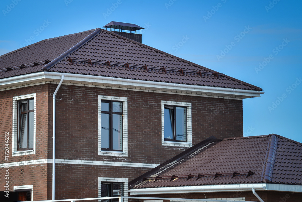 The upper part of the new brick brown house with tiled roof