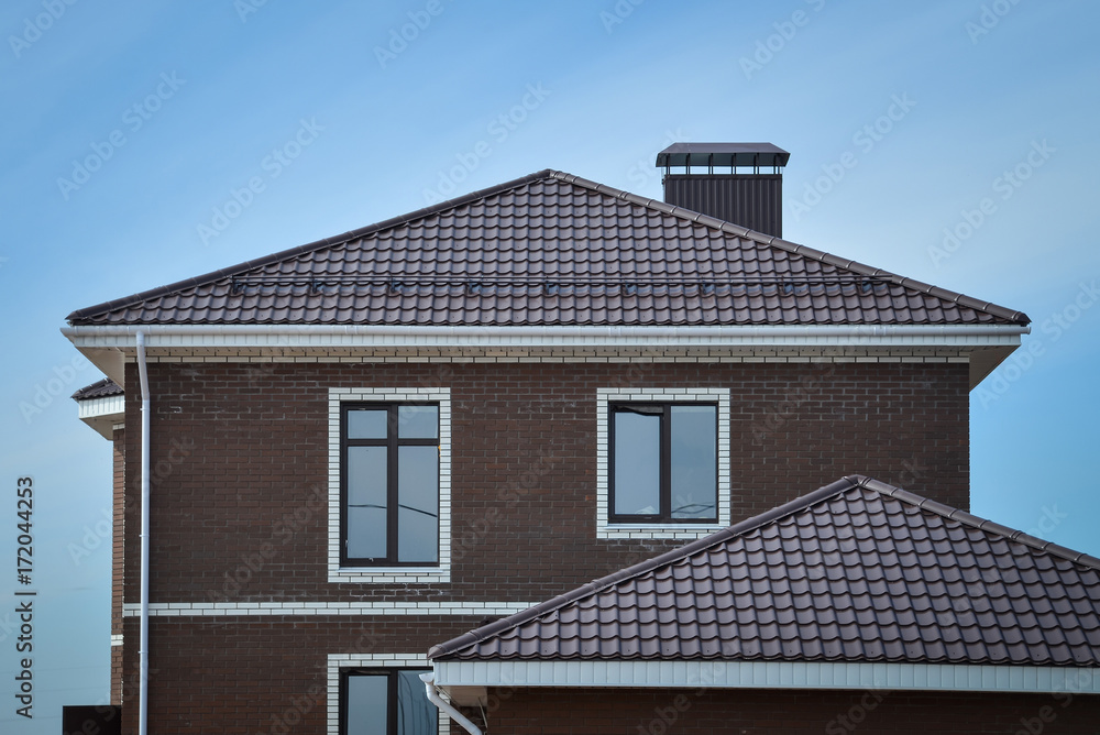 The upper part of the new brick brown house with tiled roof