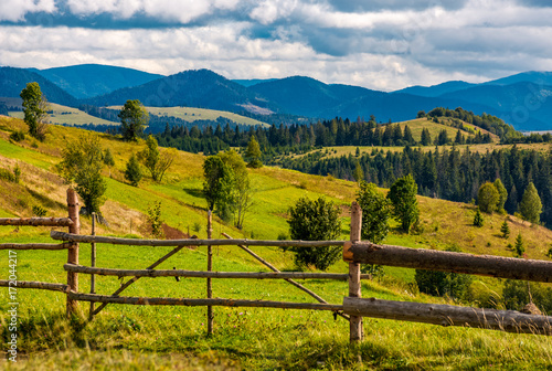 rural fields behind the wooden fence on hills in mountainous area. lovely countryside landscape in autumn