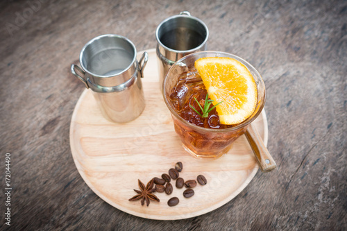 Cold brew coffee with lemon on wooden table.
