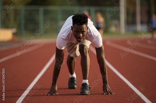 African american male sportsman ready to run on stadium track, sprint run from low start