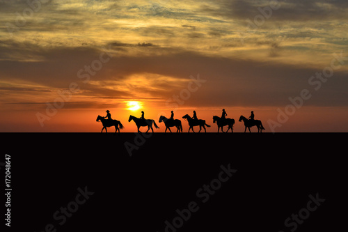 Horse rider silhouettes at sunset