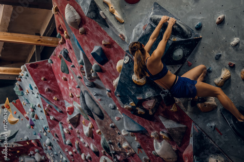 Free climber female bouldering indoors.