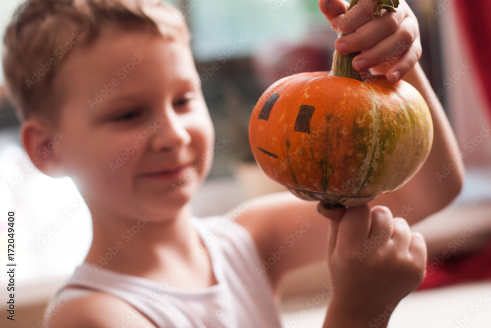 Fototapeta premium The child looks at the Jack-o-lantern,