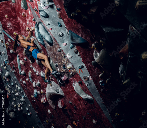 Professional female climber on a bouldering wall.